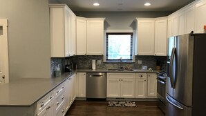 A modern kitchen with white cabinets, a stainless steel refrigerator, and a window above the sink.