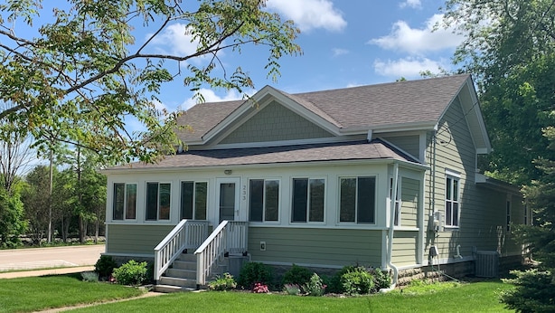 A two-story house with a front porch, a driveway, and a well-maintained lawn.
