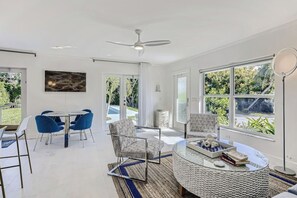Una sala de estar moderna con comedor, ventanas amplias y un ventilador de techo.