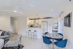 Una cocina moderna con armarios blancos, una isla central y taburetes de bar.