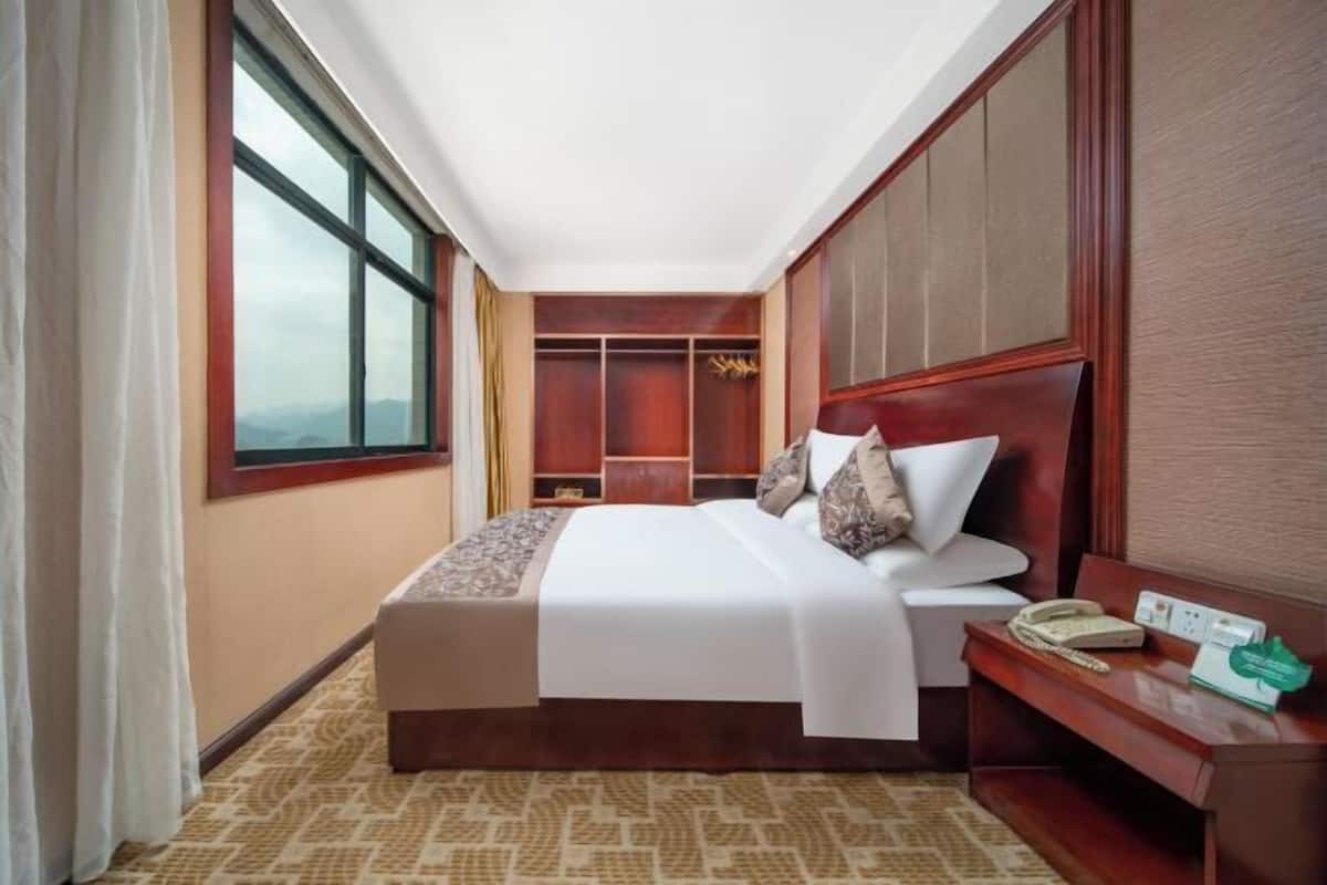Une chambre d’hôtel avec un grand lit, un bureau avec un téléphone et une armoire.