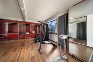 Habitación de hotel con un área de ejercicio, un espejo grande y vistas a la ciudad.