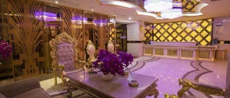 A luxurious lobby with ornate furniture, a reception desk, and decorative lighting.