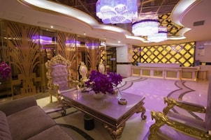 A luxurious lobby with ornate furniture, a reception desk, and decorative lighting.
