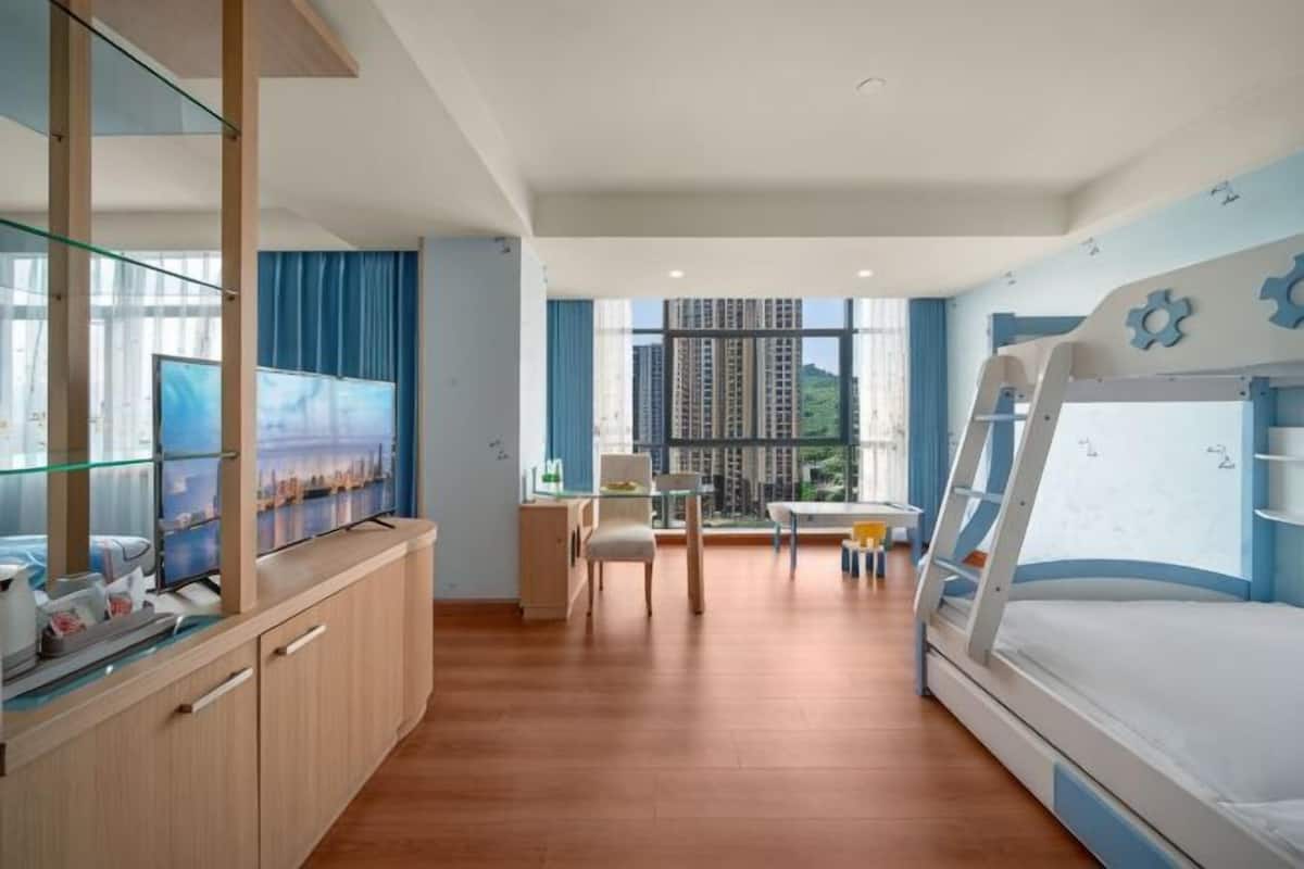 Une chambre d’hôtel moderne équipée d’un lit superposé, d’un bureau, d’une chaise et d’un téléviseur.