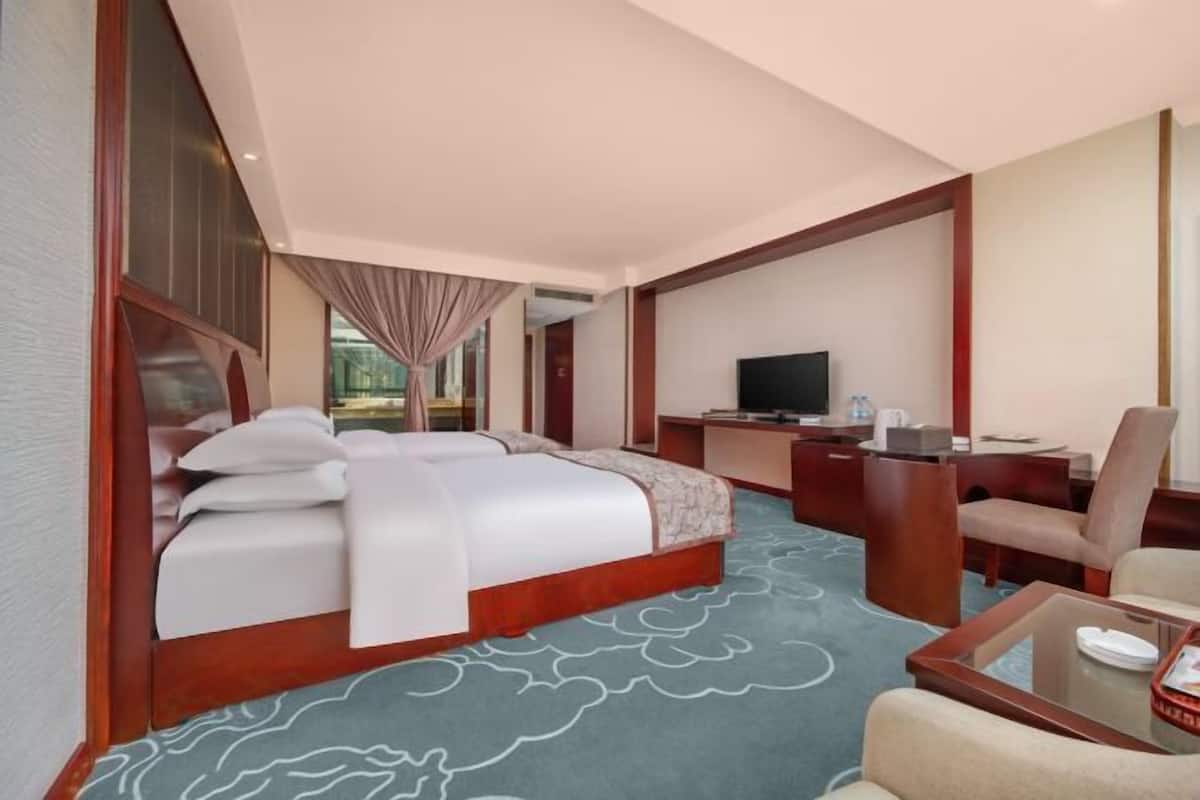 Une chambre d’hôtel dotée d’un grand lit, d’un bureau, d’une télévision et d’un coin salon.