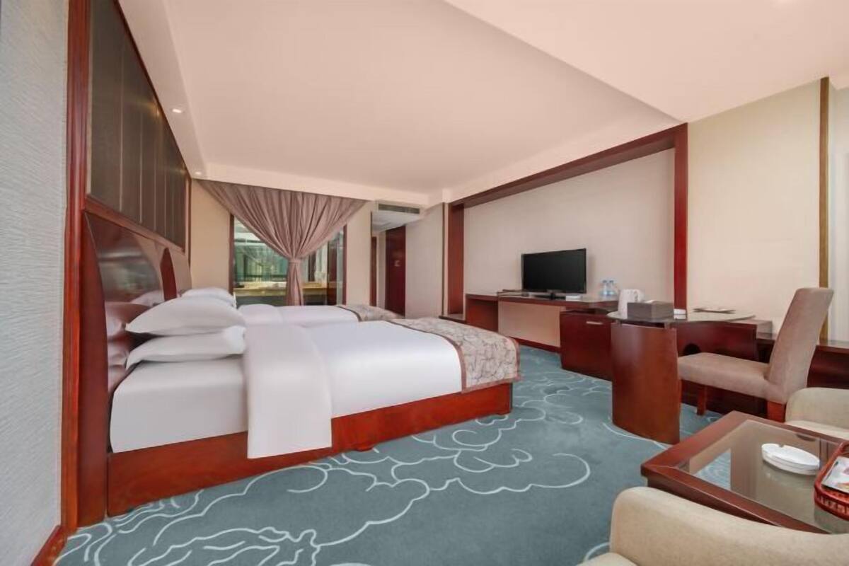 Ein Hotelzimmer mit einem großen Bett, einem Schreibtisch, einem Fernseher und einer Sitzecke.