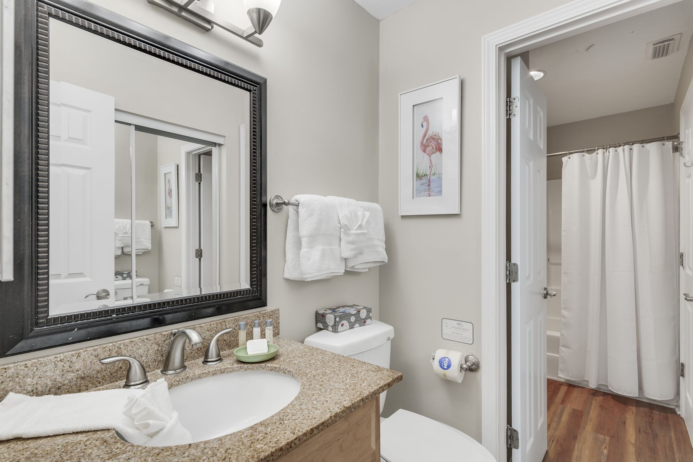 A bathroom with a sink, mirror, toilet, and shower curtain.