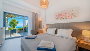 Een hotelkamer met een bed, een bureau, een stoel, een lamp en uitzicht op zee.