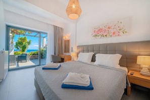Ein Hotelzimmer mit Bett, Schreibtisch, Stuhl, Lampe und Meerblick.