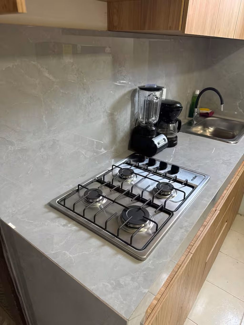 Een keuken met een gasfornuis, een blender en een spoelbak.