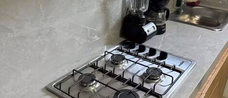 A kitchen with a gas stove, a blender, and a sink.
