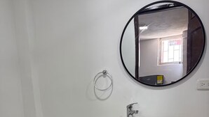Une salle de bain comprenant des toilettes, un lavabo avec un miroir au-dessus et un meuble en bois en dessous.