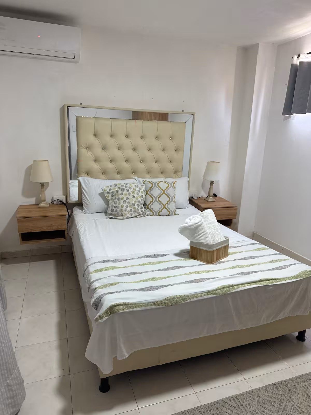 A neatly made bed with a striped bedspread, two bedside lamps, and a bedside table with a lamp.