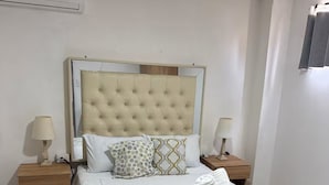 Un lit bien fait, recouvert d’une couvre-lit à rayures, avec deux lampes de chevet et une table de chevet sur laquelle se trouve une lampe.