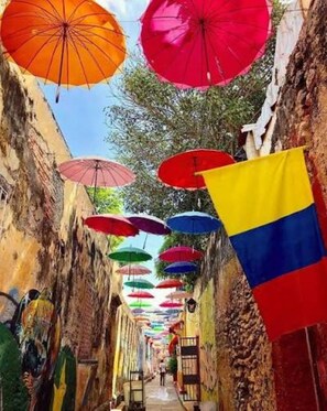A narrow alley with colorful umbrellas and flags, suggesting a vibrant atmosphere.