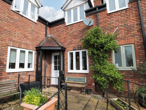 A brick house with a small front garden, a bench, and a satellite dish.