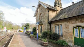 A stone building with a green door, a sign reading "Sleighs," and a railway track.