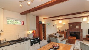 Una sala de estar acogedora con chimenea, un comedor con mesa de madera y una cocina con armarios blancos y lavadora.