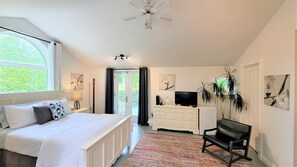 A bedroom with a bed, a desk, a chair, a TV, and a plant. - Auberge du Vignoble Bromont (Brigham)