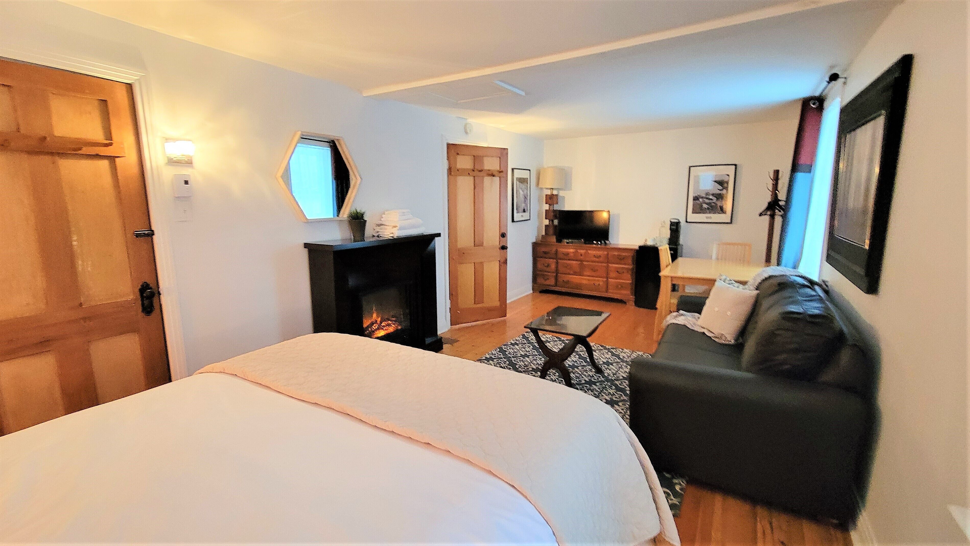 A bedroom with a large bed, a fireplace, a sofa, and a television.