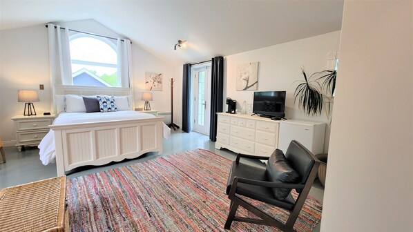 A bedroom with a bed, bedside tables, a TV, a dresser, and a chair.