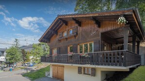 A wooden chalet with a balcony, a wooden door, and a window with shutters.