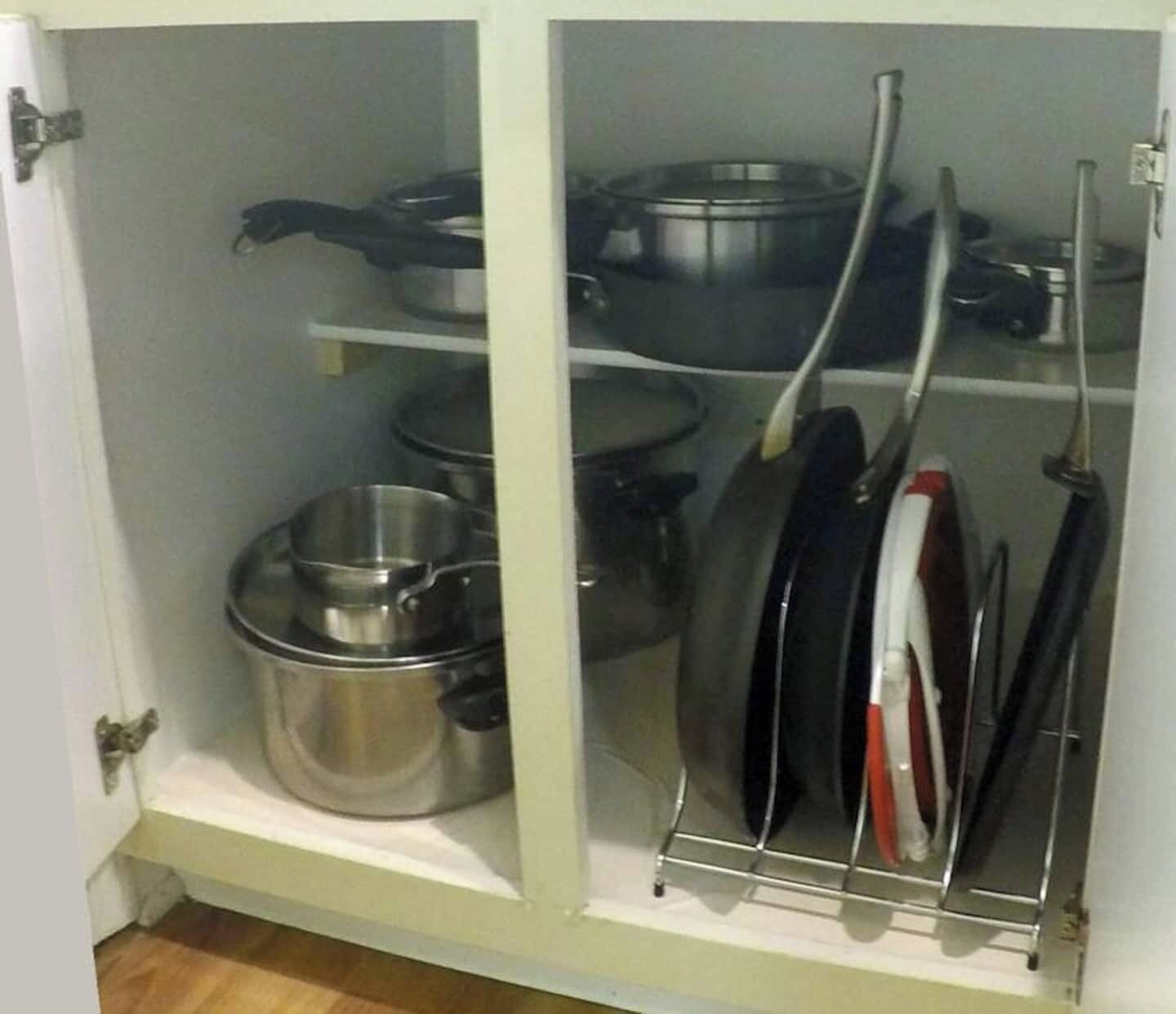 Een keukenkastje met pannen, kookgerei en bestek.