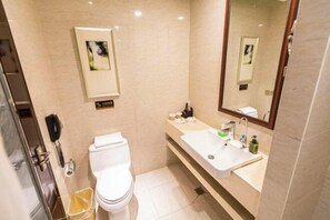 Un baño con inodoro, lavamanos, espejo y cubo de basura.