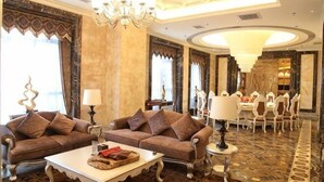A hotel lobby with two sofas, a coffee table, a chandelier, and a dining area with chairs and a table. - Pidu International Hotel (Xinji)