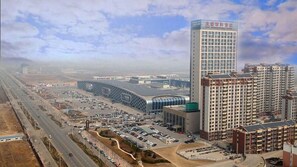 Un complexe hôtelier moderne comprenant plusieurs immeubles de grande hauteur, un parking et une structure incurvée dotée d’une façade en verre.