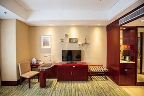 Ein Hotelzimmer mit Flachbildfernseher, Schreibtisch, Stuhl, Sofa, kleinen Tisch und Schrank.