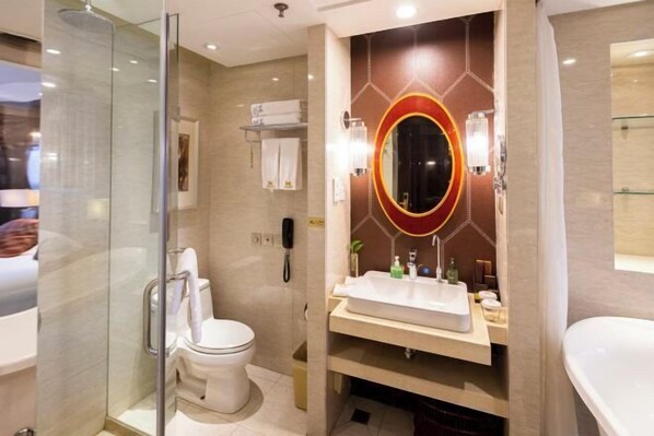 Uma casa de banho moderna com cabine de duche em vidro, sanita, lavatório com bancada e um espelho grande com moldura decorativa.