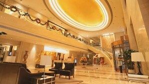 A spacious lobby with a grand staircase, a reception desk, and modern furnishings. - Pidu International Hotel (Xinji)