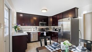 A modern kitchen with dark wood cabinets, stainless steel appliances, and a checkered tablecloth.