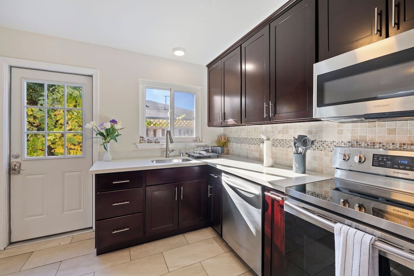 A modern kitchen with dark cabinets, a stainless steel microwave, and an oven.