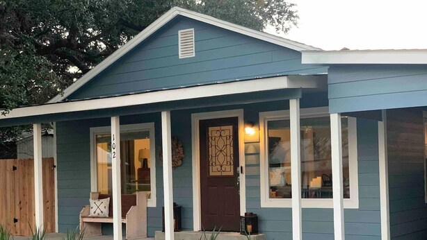 A two-story house with a covered porch, a front door, and a mailbox.