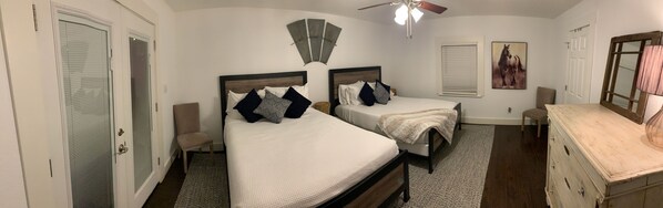 A bedroom with two beds, a ceiling fan, a dresser, and a painting on the wall.