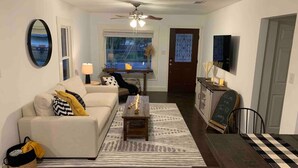 A living room with a sofa, coffee table, and a dining area with a table and chairs.