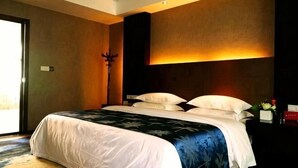 A bedroom with a bed, a nightstand, a lamp, and a view of the outdoors. - Jinhong Hotel (Zheng'an)