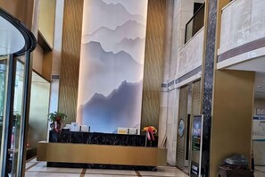 A reception area with a marble counter, a wall mural, and a vertical column.