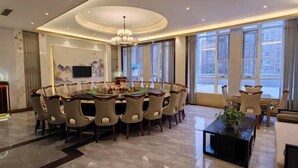 A spacious dining area with a round table, multiple chairs, and a chandelier. - Jinhong Hotel (Zheng'an)