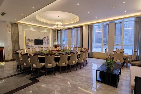 A spacious dining area with a round table, multiple chairs, and a chandelier. - Jinhong Hotel (Zheng'an)
