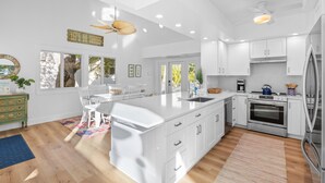 A modern kitchen with white cabinetry, a large island, and a built-in oven.