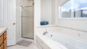 A bathroom with a walk-in shower, a bathtub, and a window providing a view of the outside. - Unique triangle shaped home with 2 master suites on separate floors. (Cheyenne)