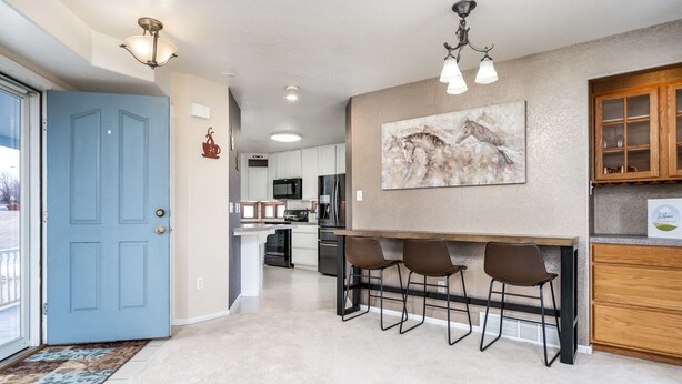 A modern kitchen with a blue door, a dining area with bar stools, and a large painting on the wall. - Unique triangle shaped home with 2 master suites on separate floors. (Cheyenne)