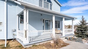 A light blue two-story house with a white porch and a small garden area. - Unique triangle shaped home with 2 master suites on separate floors. (Cheyenne)