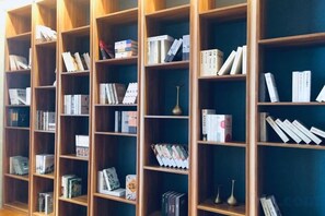 A row of wooden bookshelves filled with books and decorative items. - Ruiyi Hotel (Qinzhou)