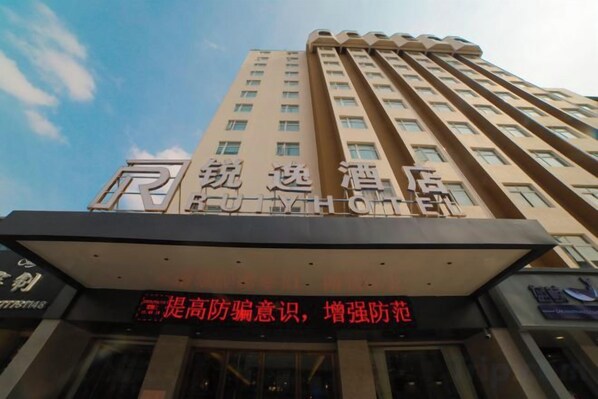 A high-rise hotel with a prominent sign and a banner with safety information. - Ruiyi Hotel (Qinzhou)