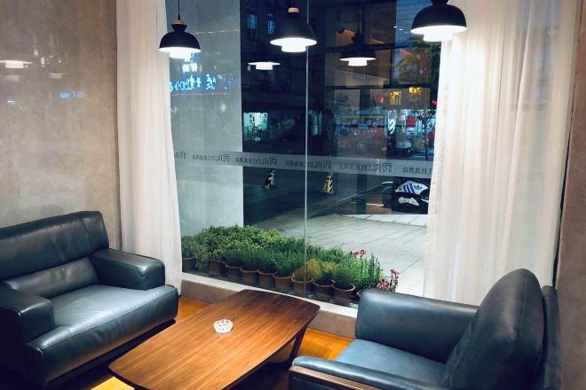 Ein modernes Interieur mit einer Couch, einem Holztisch und Blick auf die Straße durch ein großes Fenster.